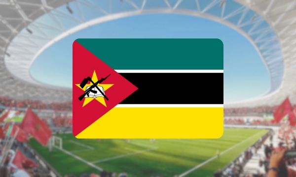 Bandeira de Moçambique exibida em um estádio de futebol com torcedores ao fundo.