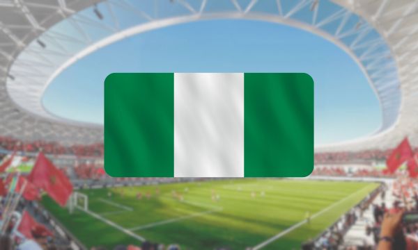 Um fundo desfocado de um estádio com a bandeira nigeriana em destaque no primeiro plano.